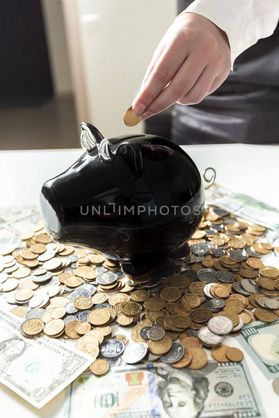 Young businesswoman putting coin in black piggy bank