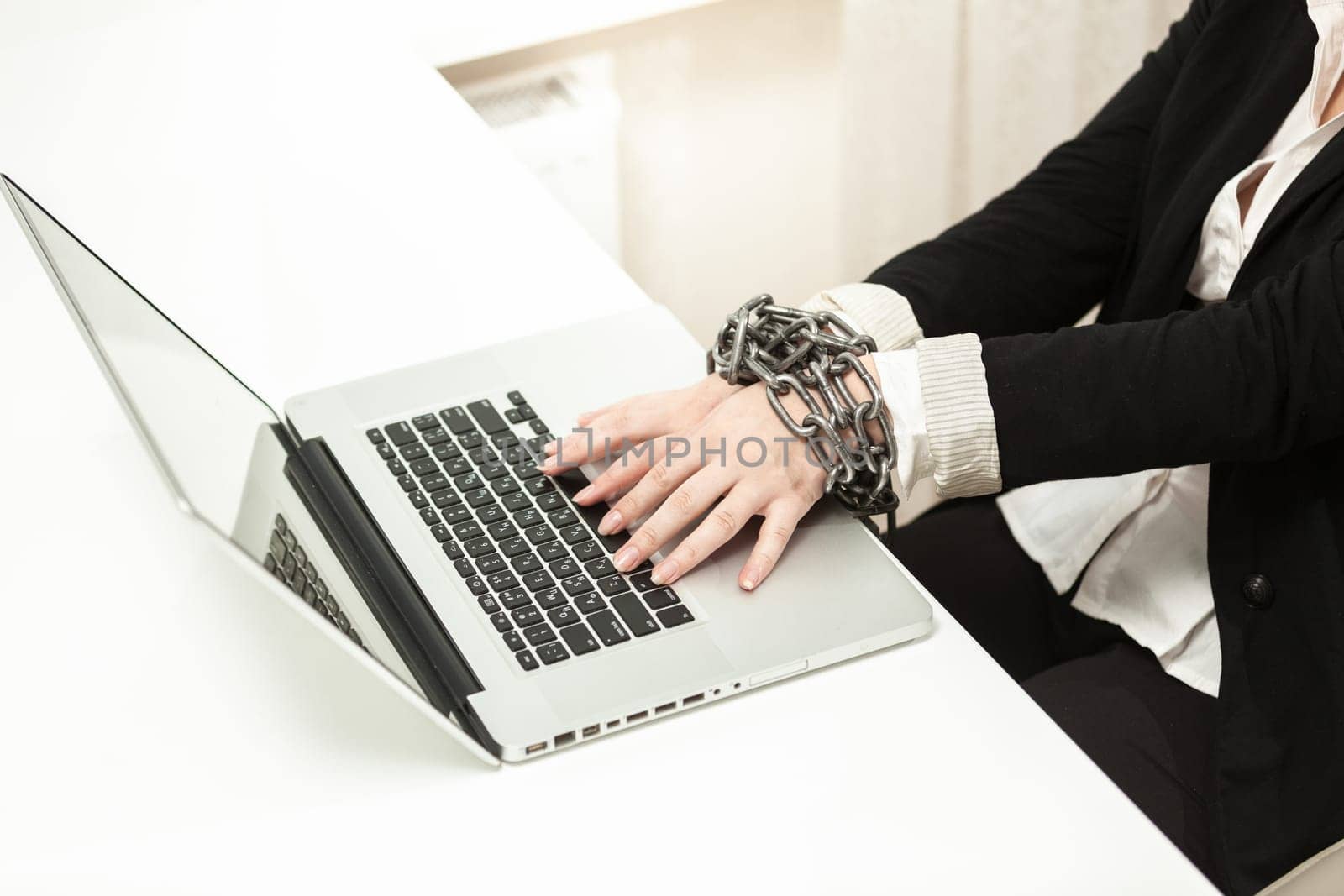 Photo of chained businesswoman typing on keyboard