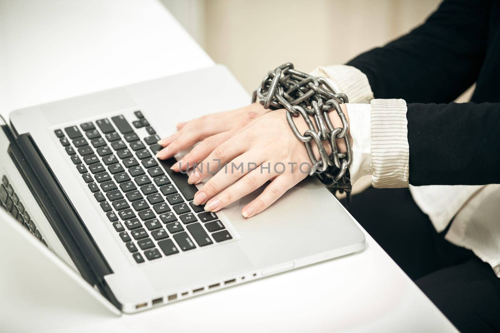Closeup photo of female hand chained up to laptop