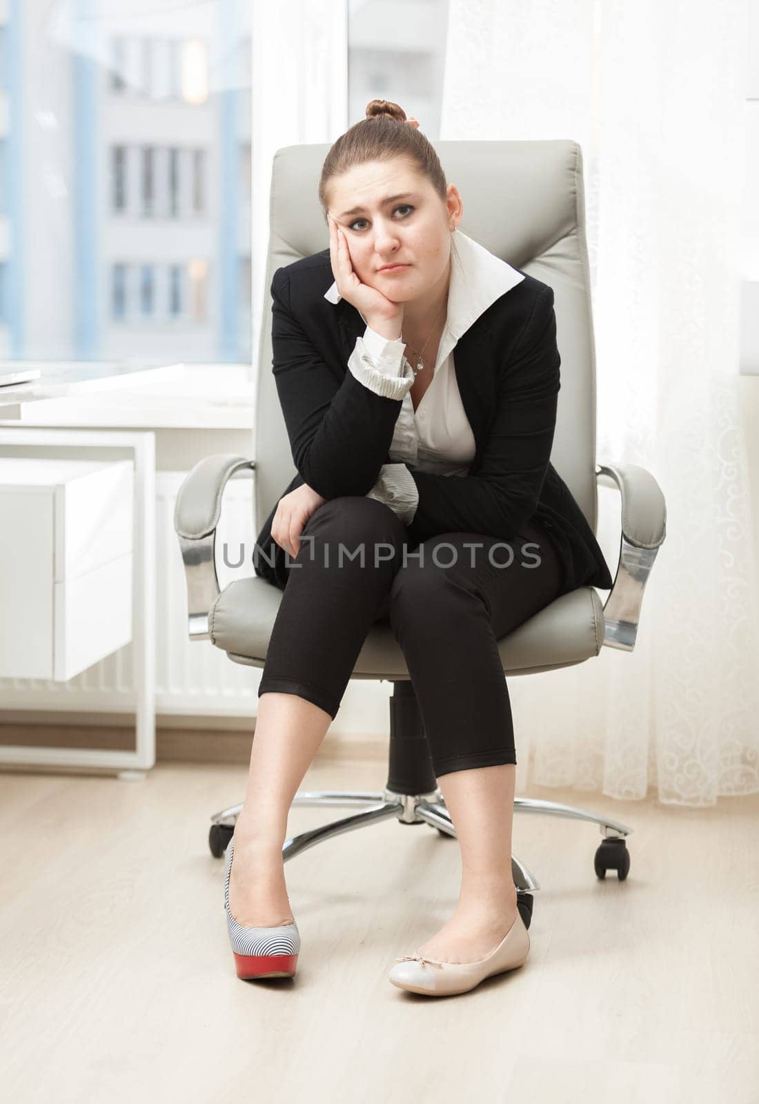Sad businesswoman choosing between high heeled shoe and ballet flat