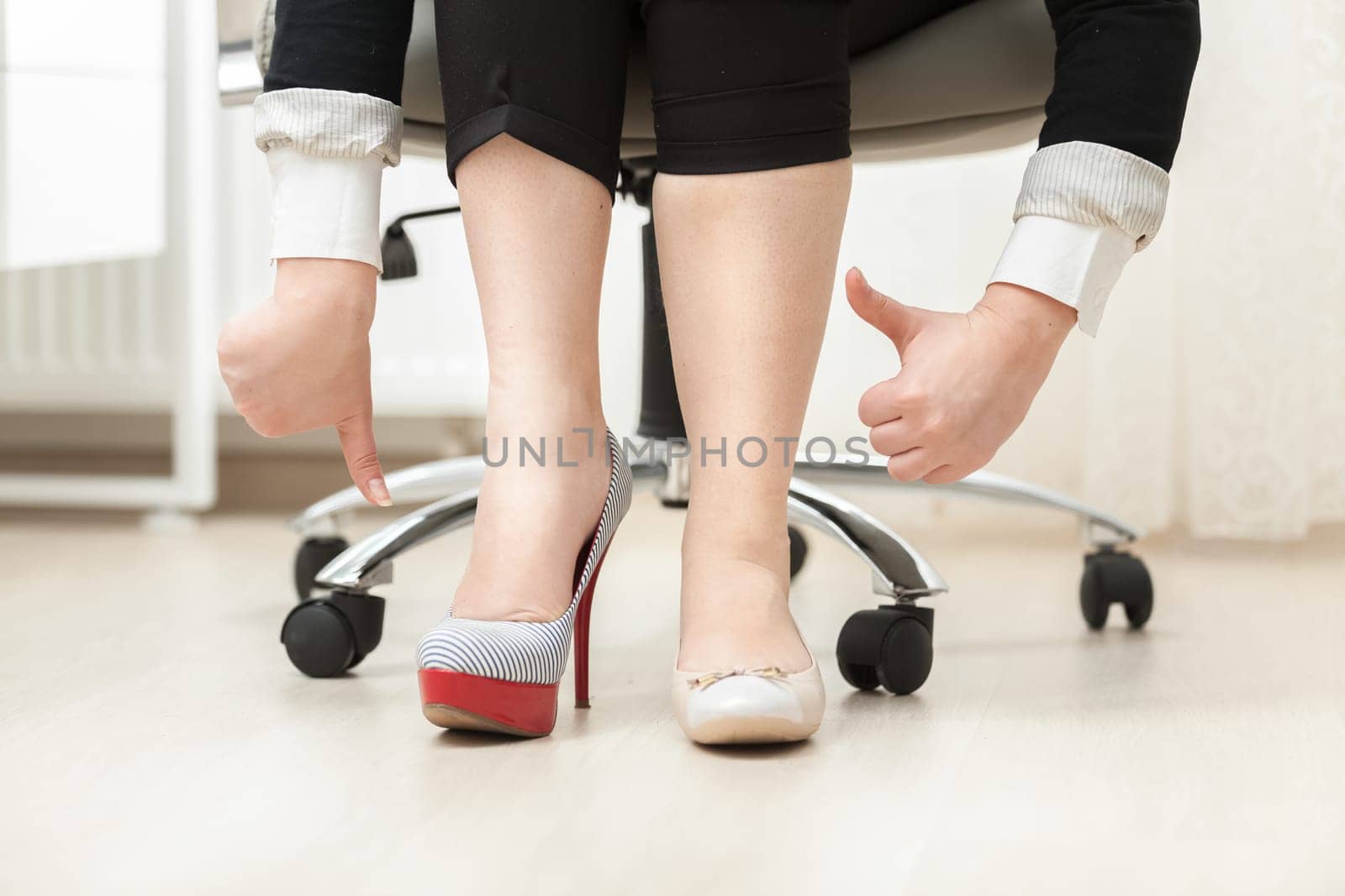 Closeup photo of woman wearing high heel shoe and ballet flat holding thumbs down and up