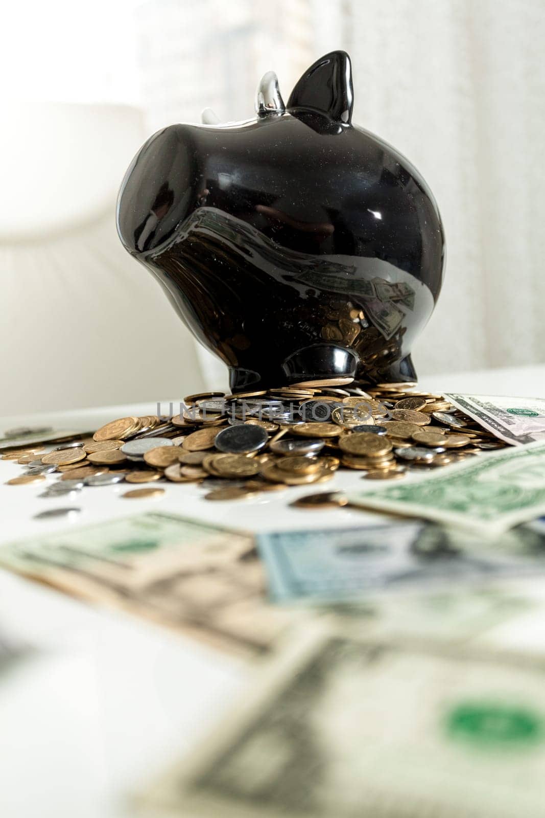 Photo of black piggy bank standing on pile of money