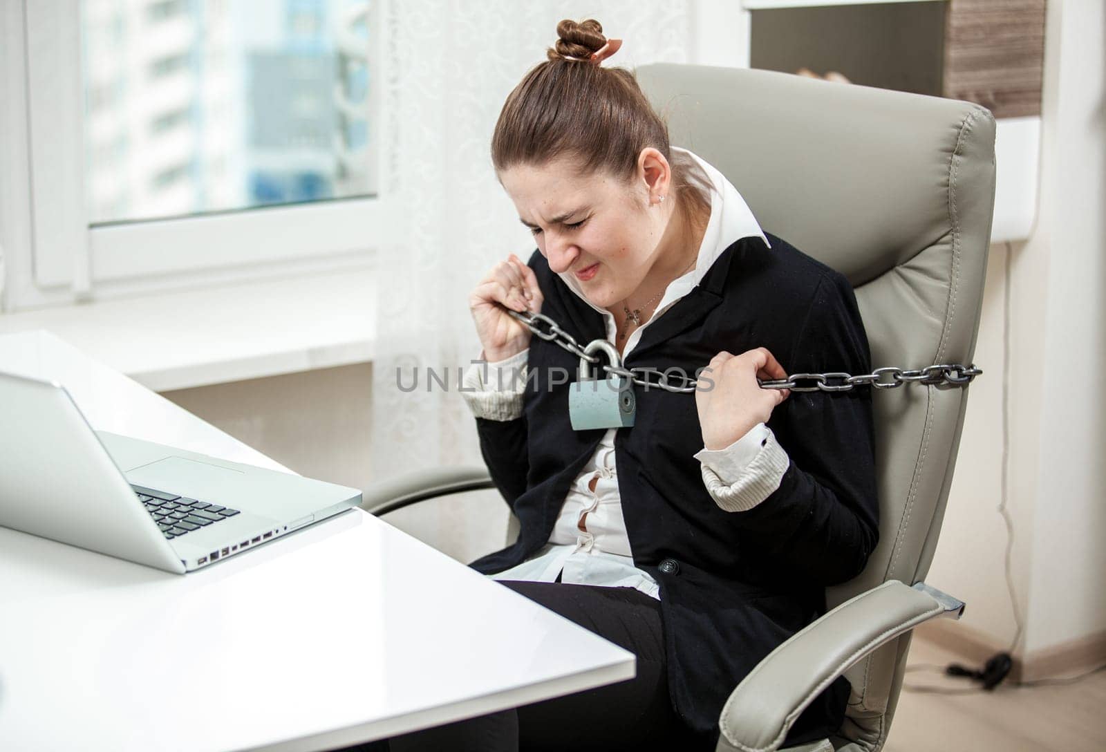 Portrait of tied businesswoman tearing apart metal chained