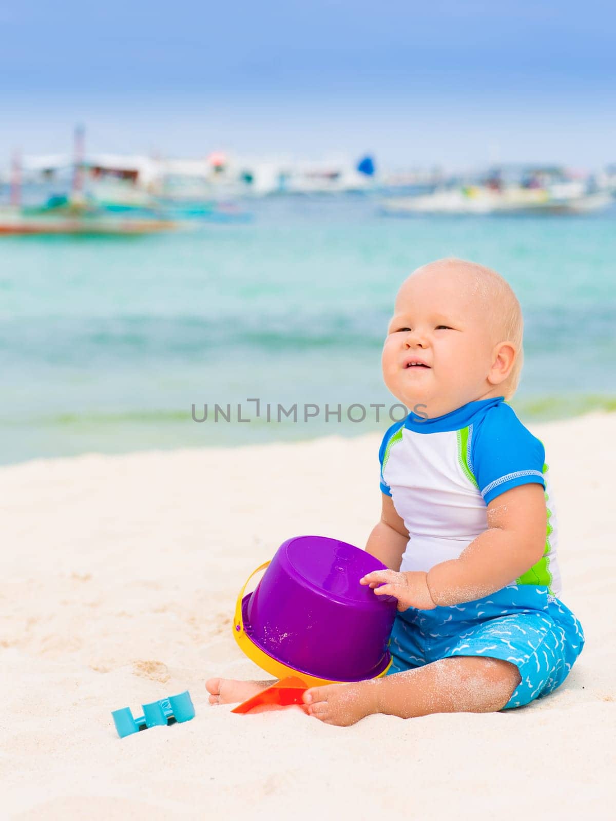 Cute baby on the tropical beach playing toys