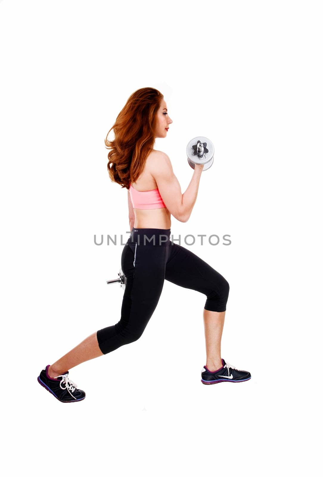 A lovely slim women in black exercise pants and sports bra working.out with dumbbell's, isolated on white background..