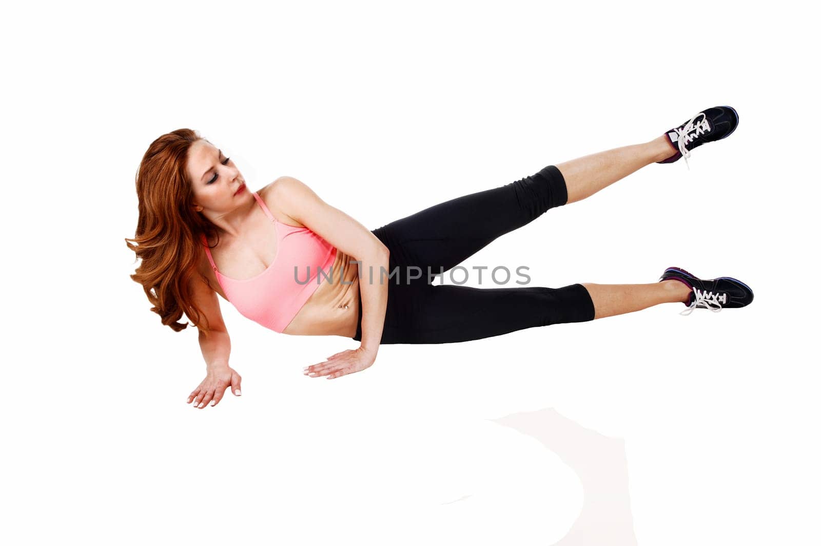 A pretty slim woman lying on the floor doing leg exercise, isolated.on white background..