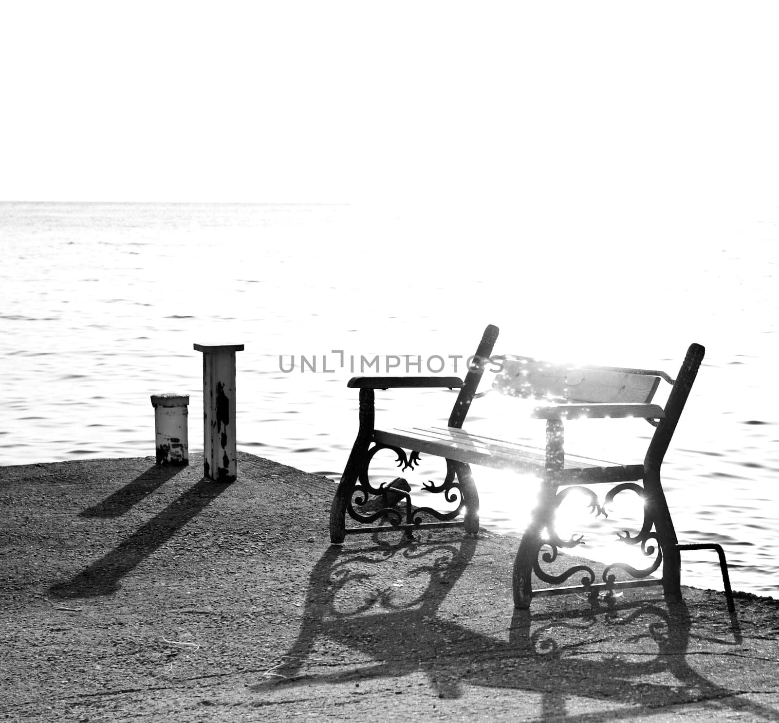 Monochromatic photo of bench on the harbour