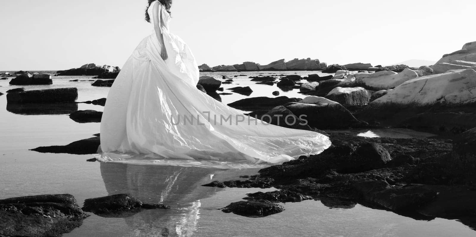 Vintage photo of beautiful bride standing on a cliff on the sea