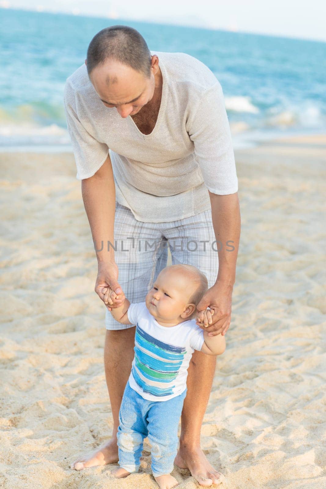 Father is helping his son to make first steps outdoor