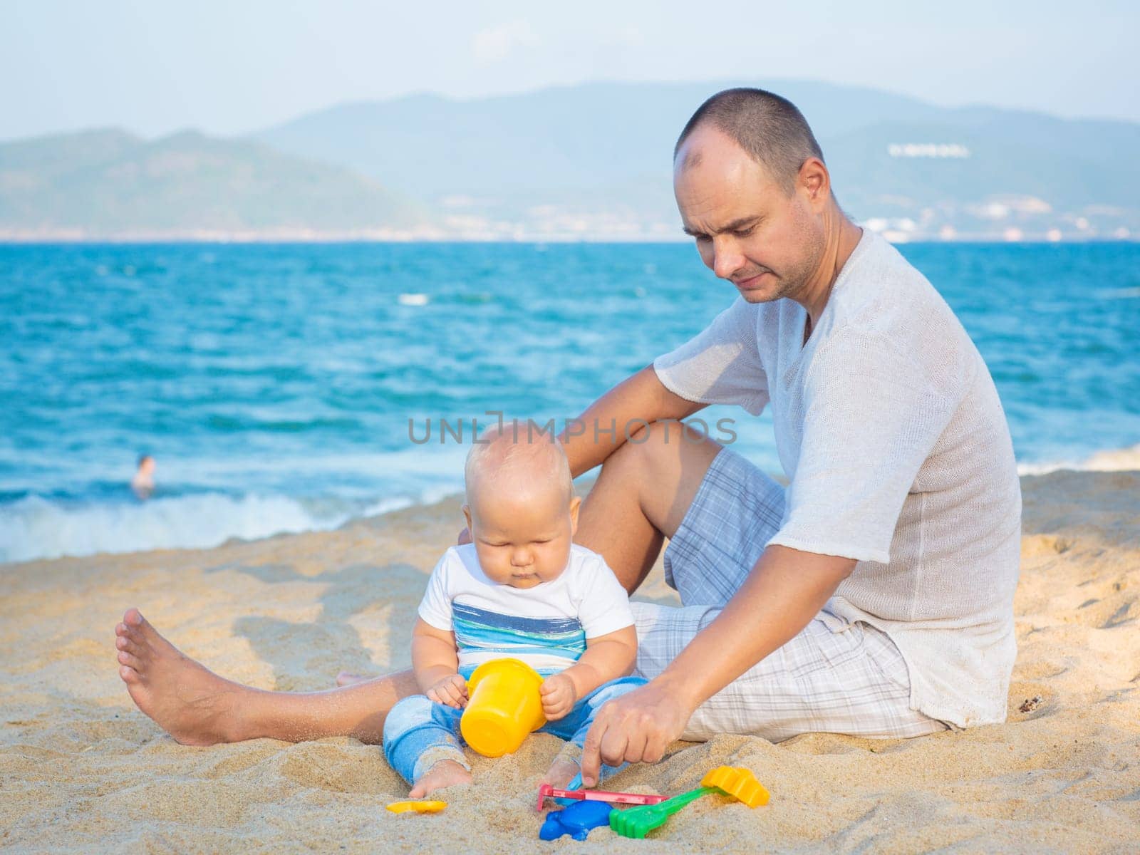 Father and baby are playing beach toys