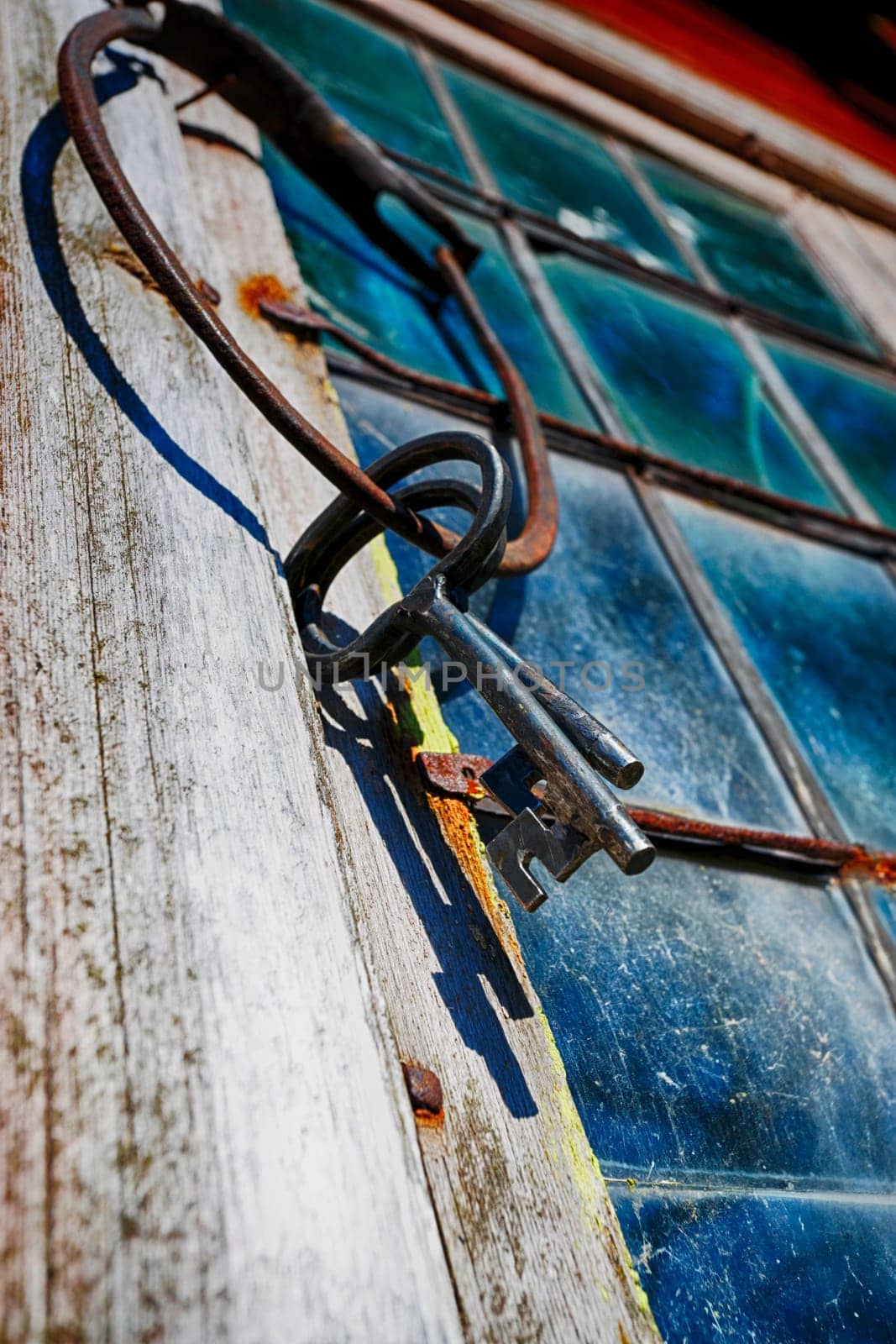 old, antique keys hanging on a stained-glass leaded window frame