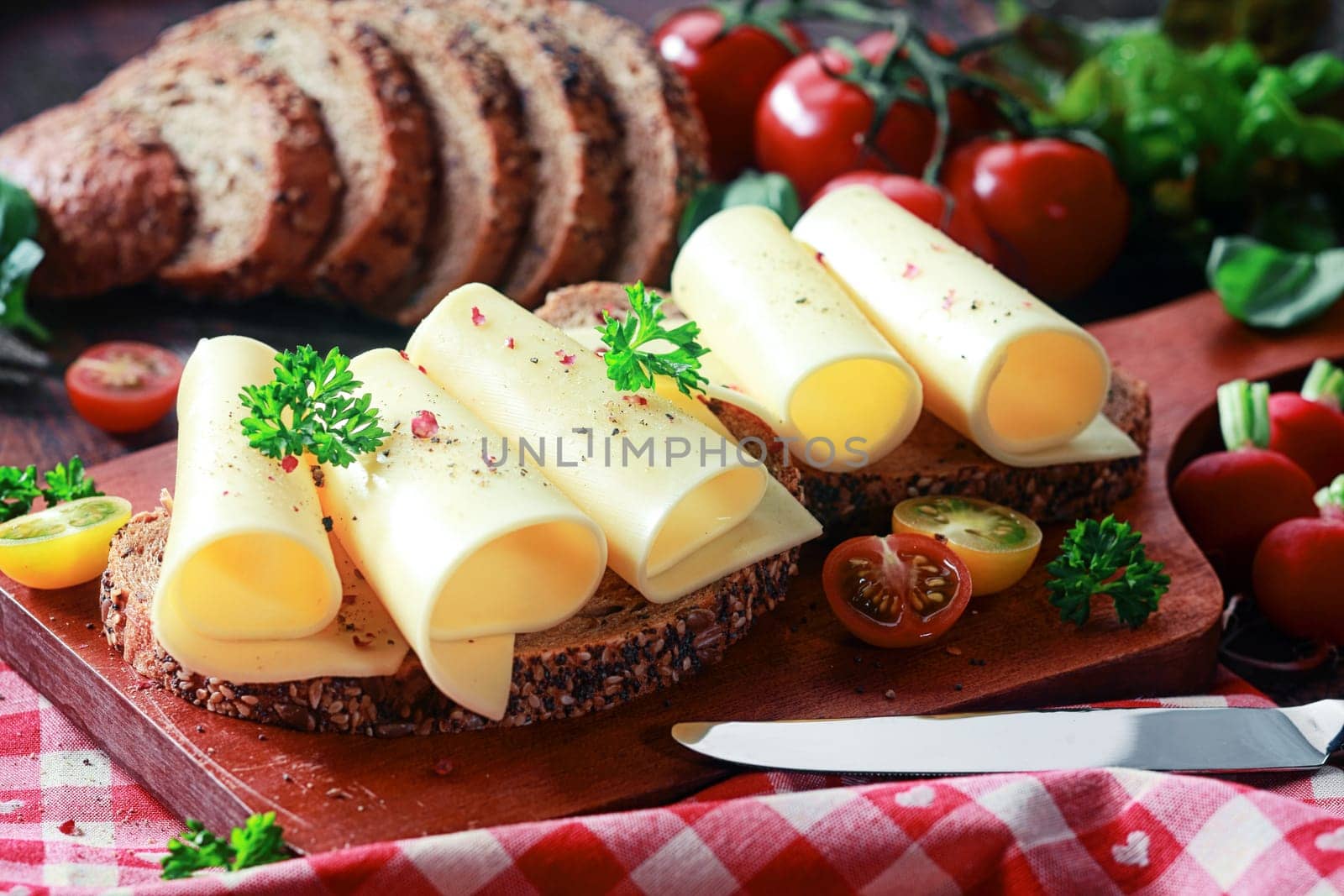Gouda cheese rolls on rye bread with parsley garnish on a wooden board in a country kitchen