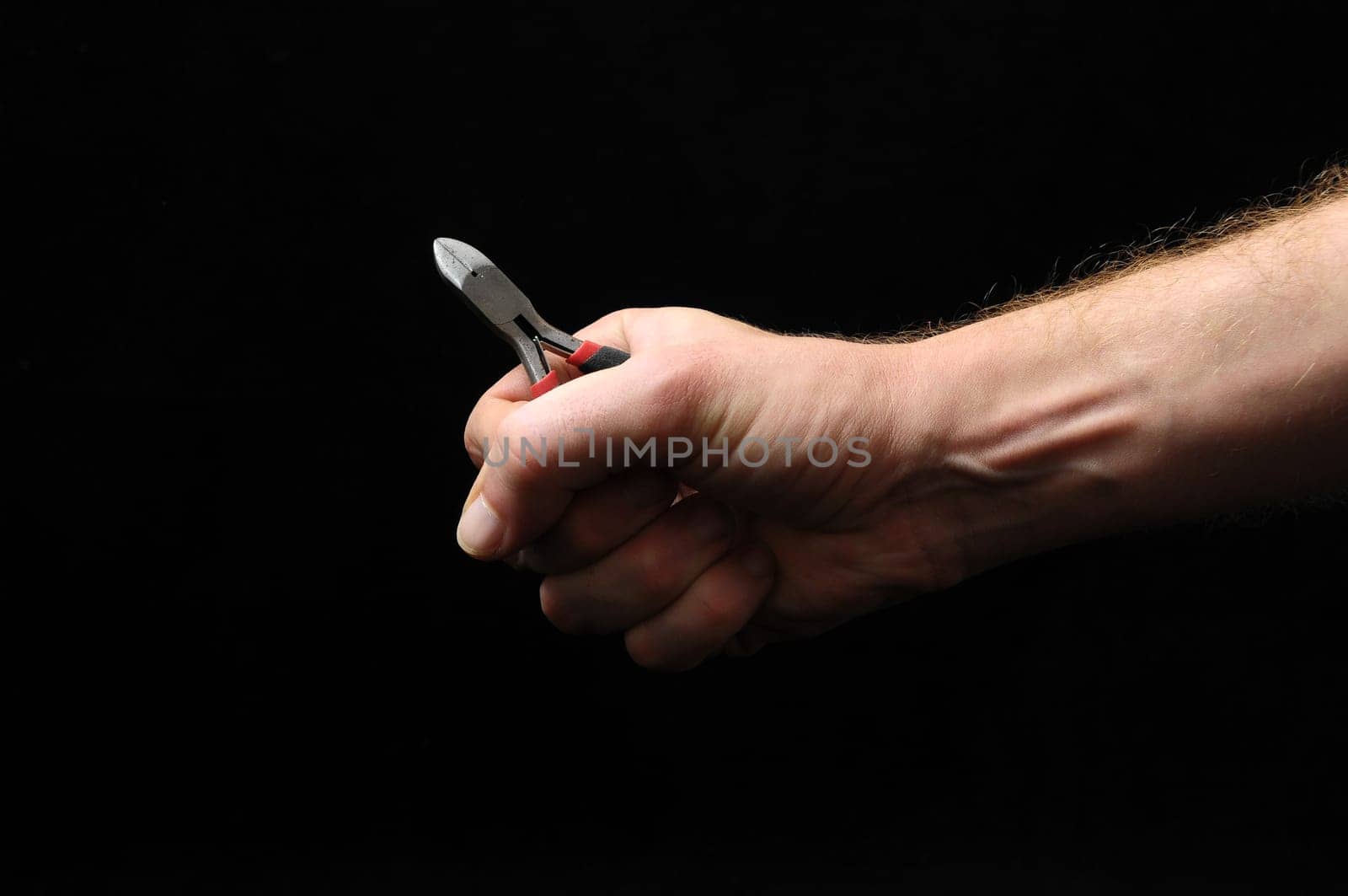 Cutter Pliers and a Hand on a Black Background