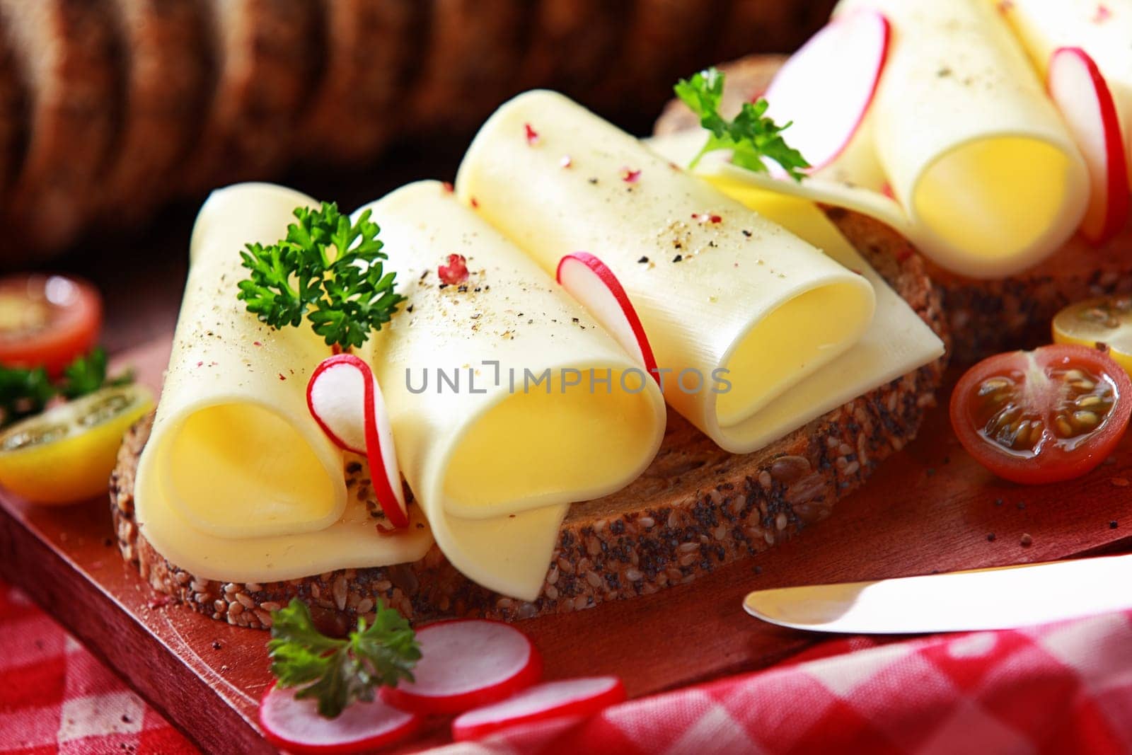 Tasty gouda cheese sandwich on wholegrain bread topped with slice radish and parsely for a healthy country lunch, close up view