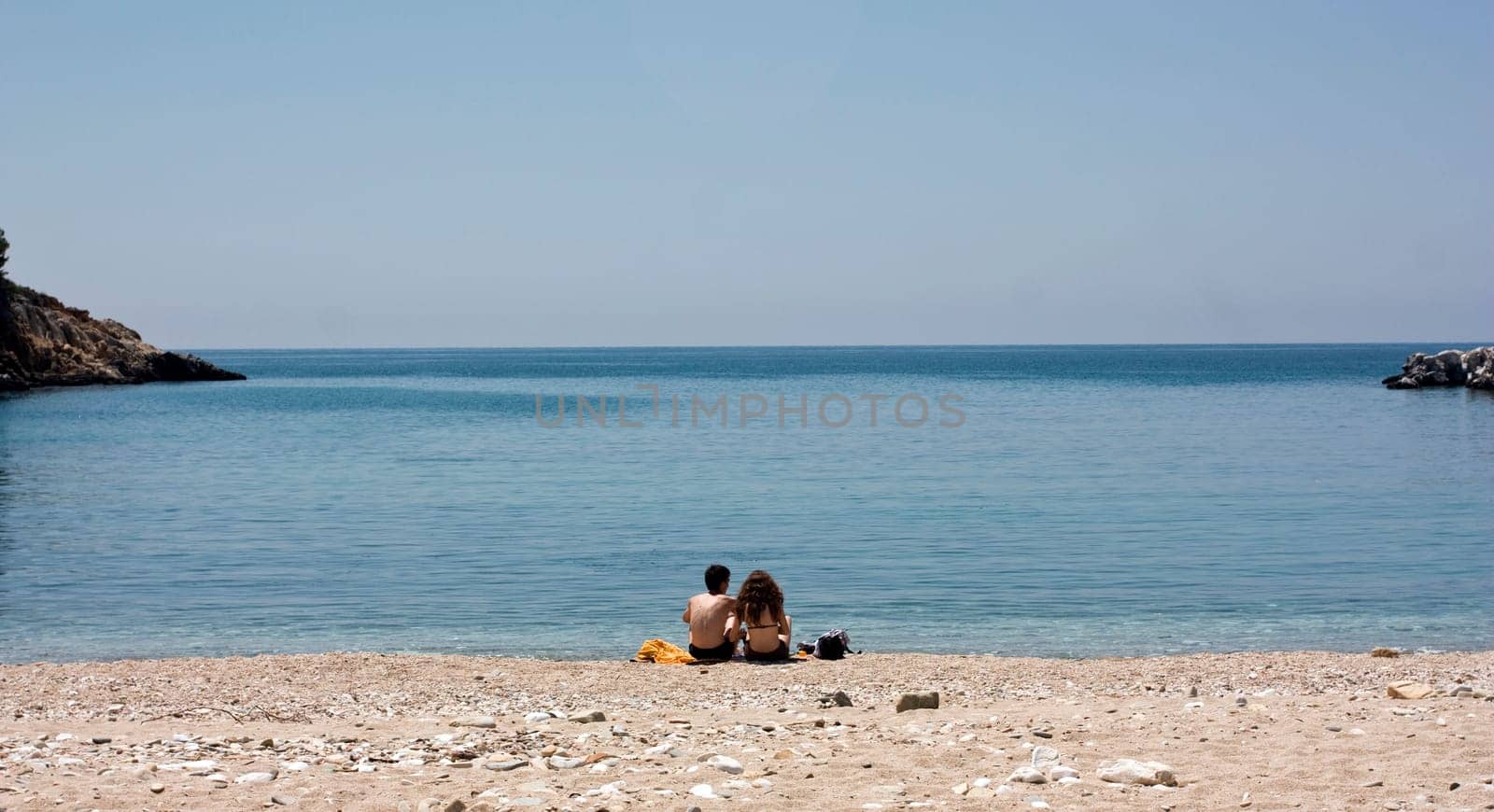 Vintage photo of a young couple sitting on the beach and looking at sea