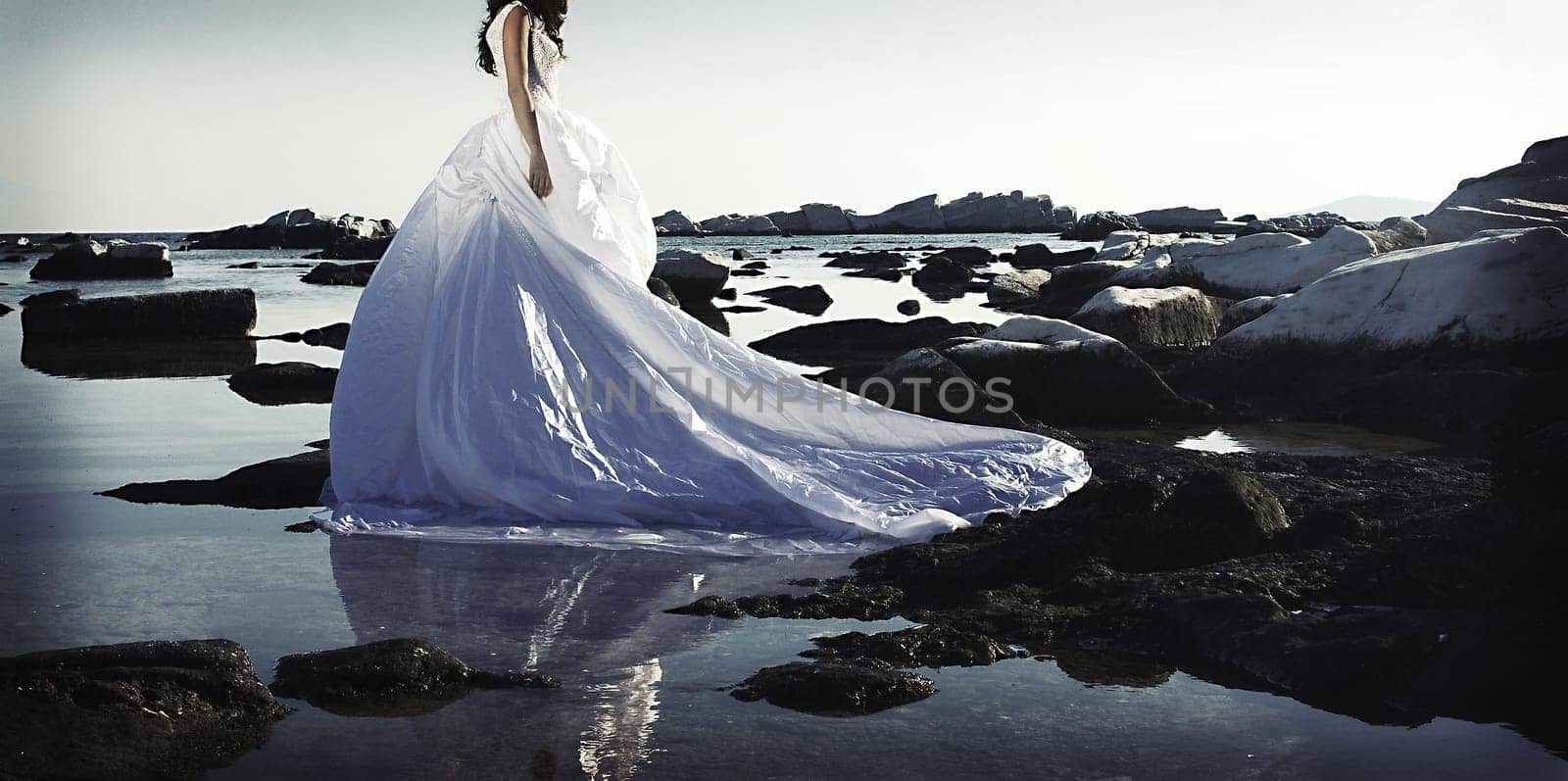 Vintage photo of beautiful bride standing on a cliff on the sea