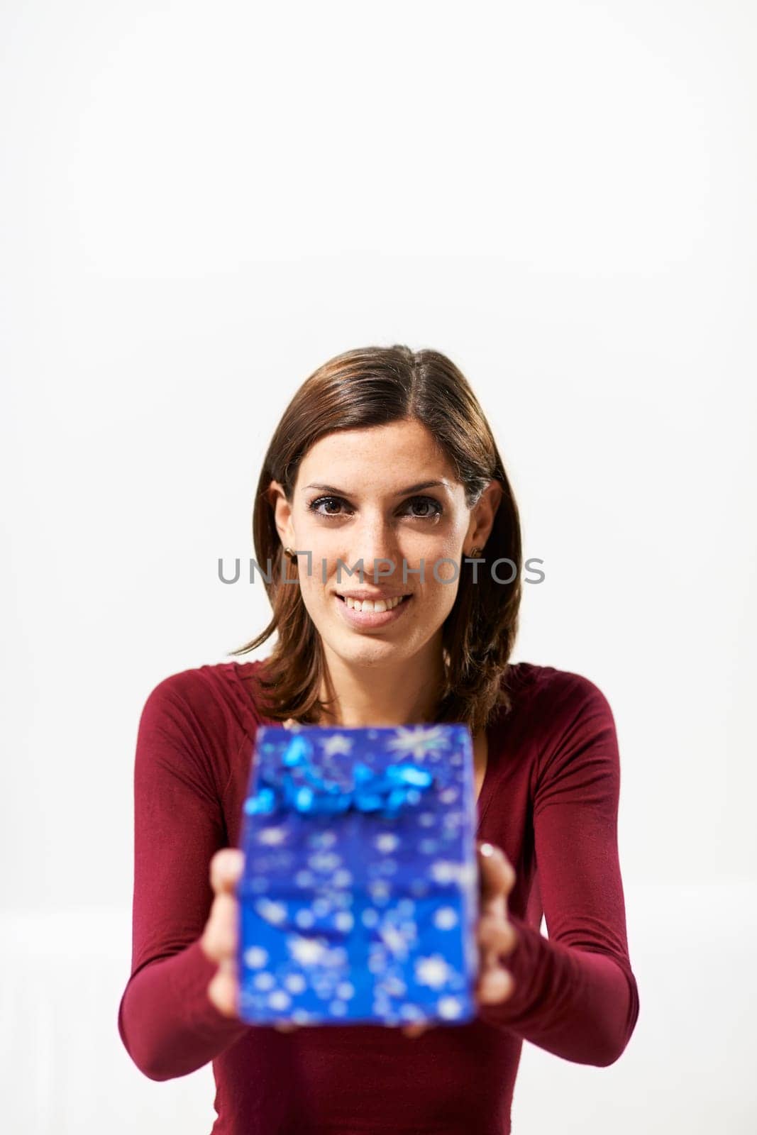 caucasian young woman showing present to the camera and smiling on white background