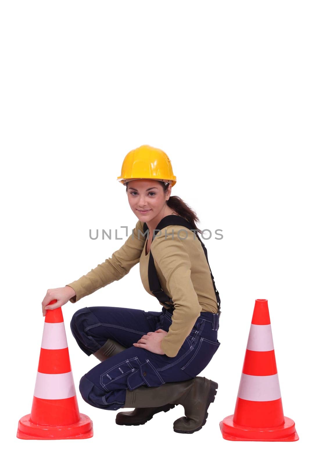 Female road worker kneeling by cones