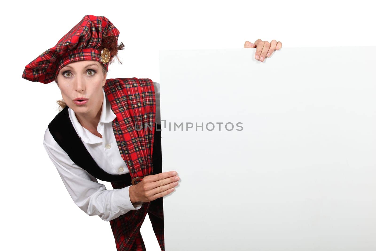 Surprised woman in traditional Scottish outfit with a board left blank for your message