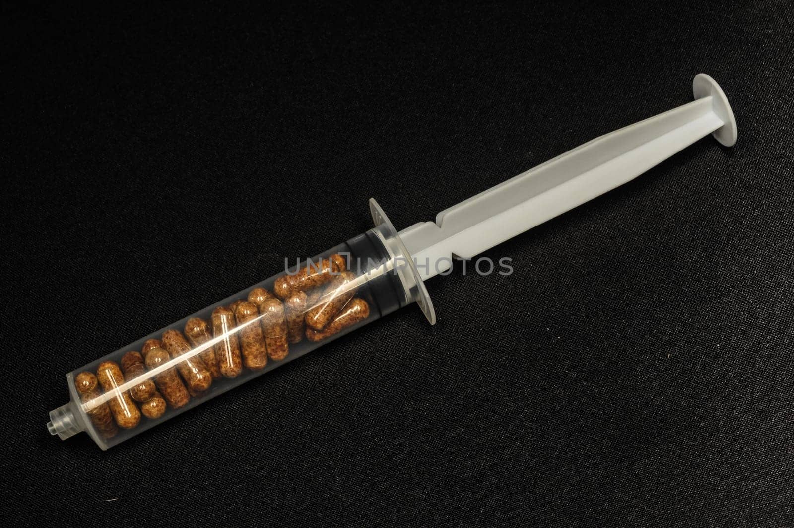 Medical Syringe Full of Pill Drugs on a Black Background