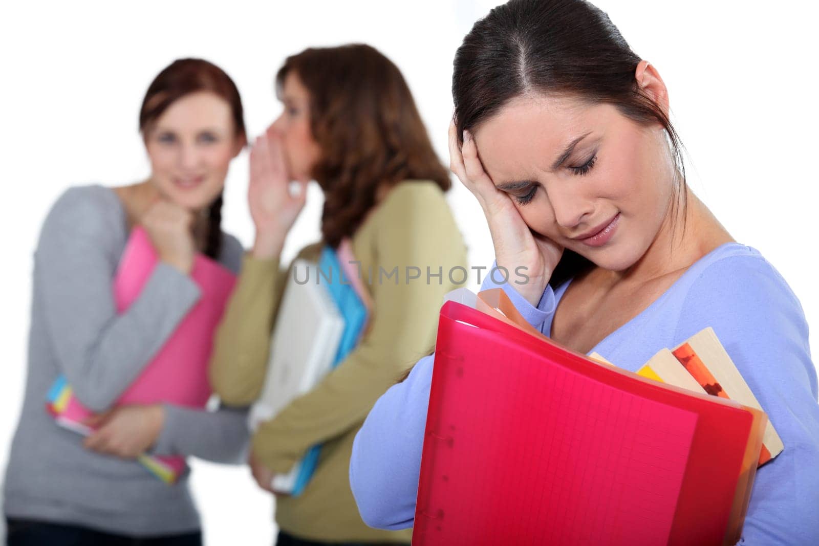 women whispering behind a confused colleague