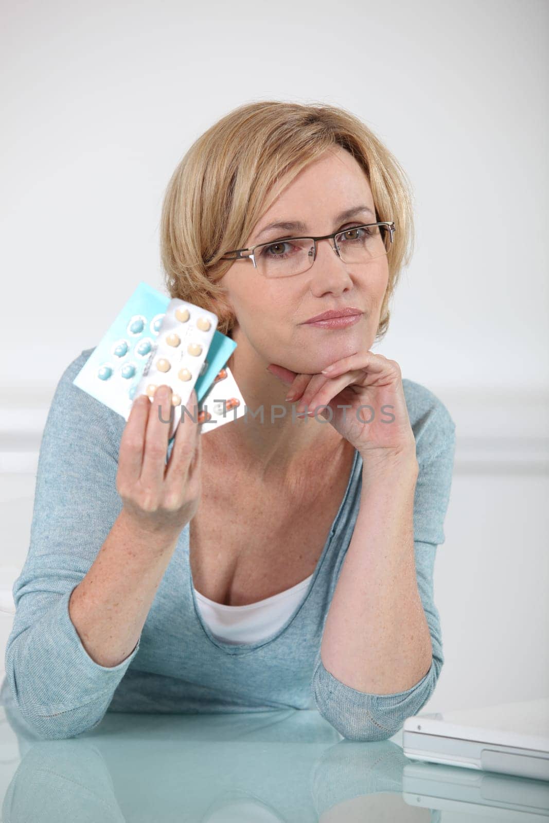 Blond woman holding various prescription drugs