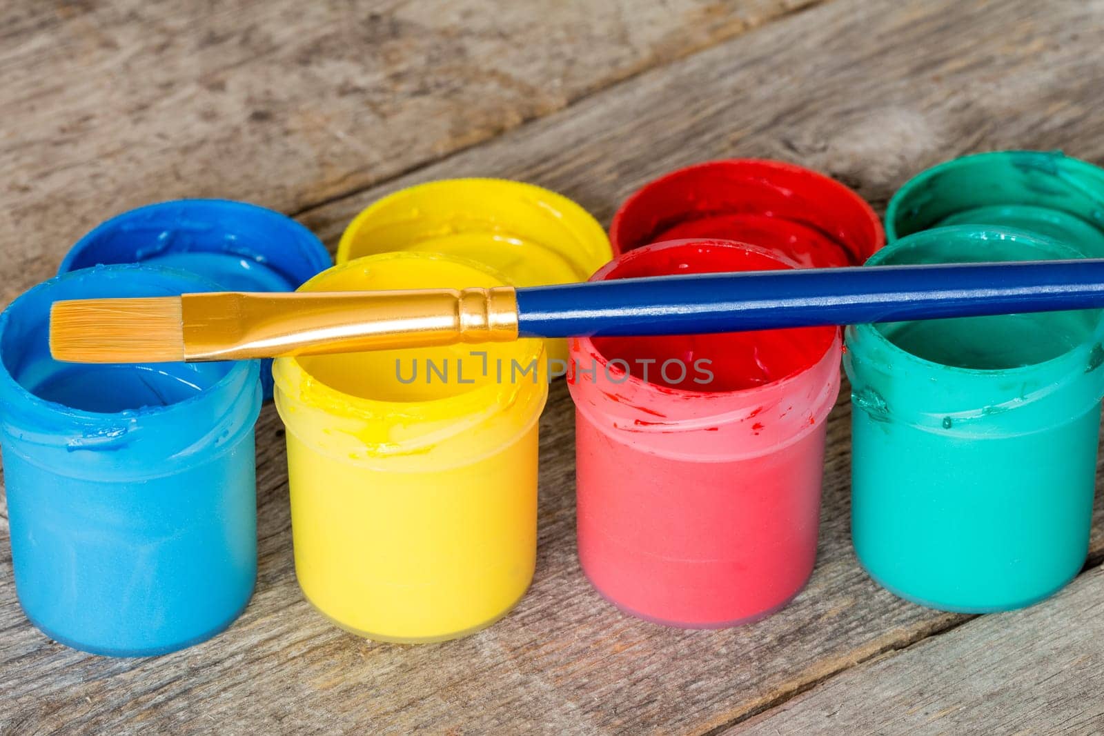 Watercolor paints with  paintbrush on the wood background