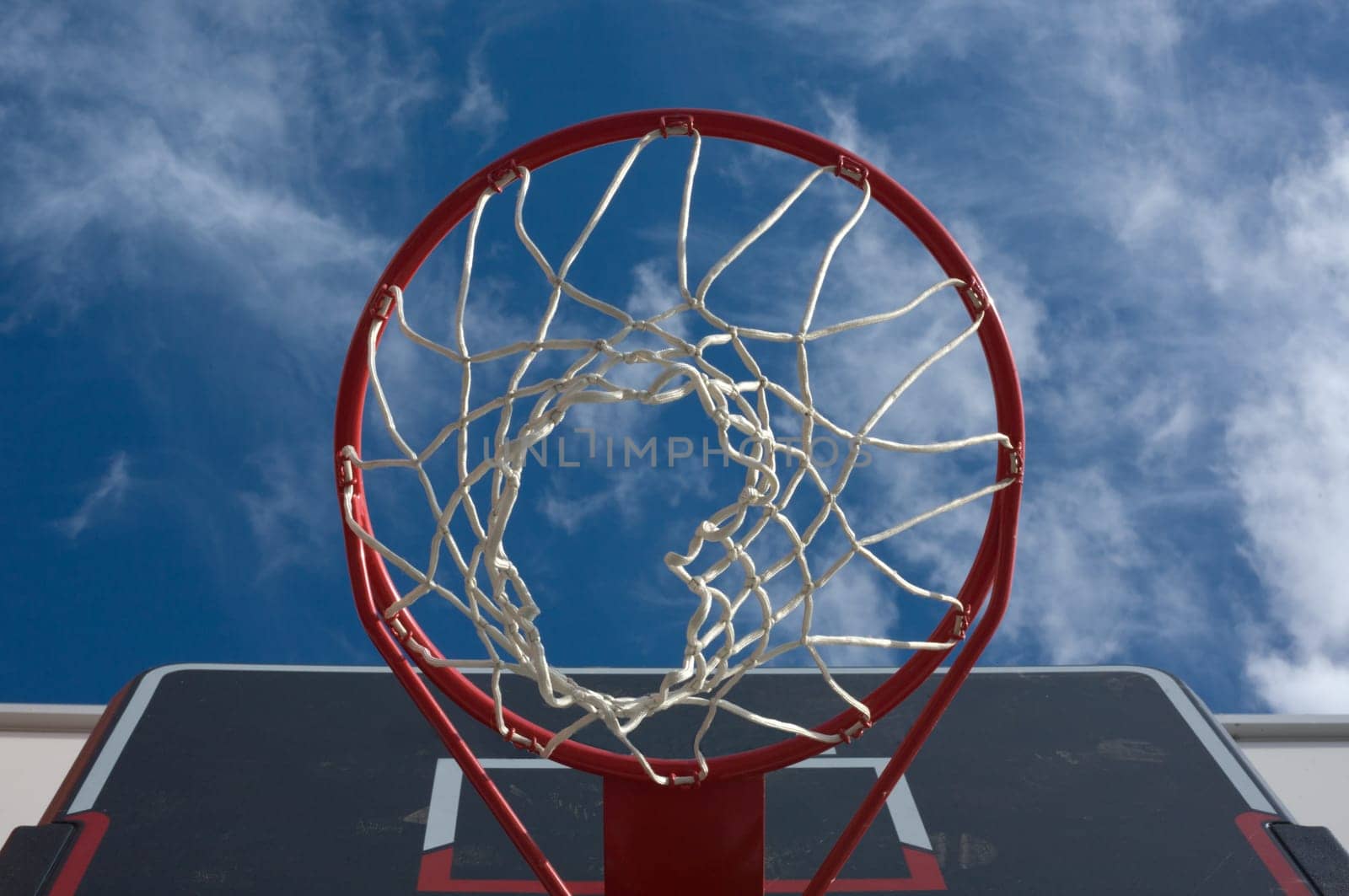 New basketball hoop from below against a cloudy sky