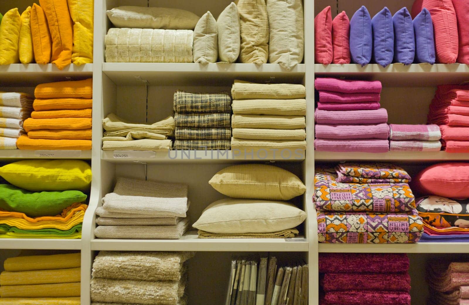 Bright pillows, towels, plaids, blankets and other home wear on shelves