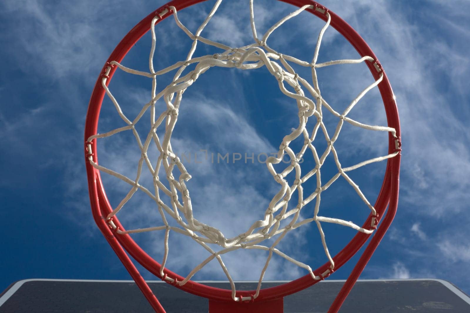 New basketball hoop from below against a cloudy sky