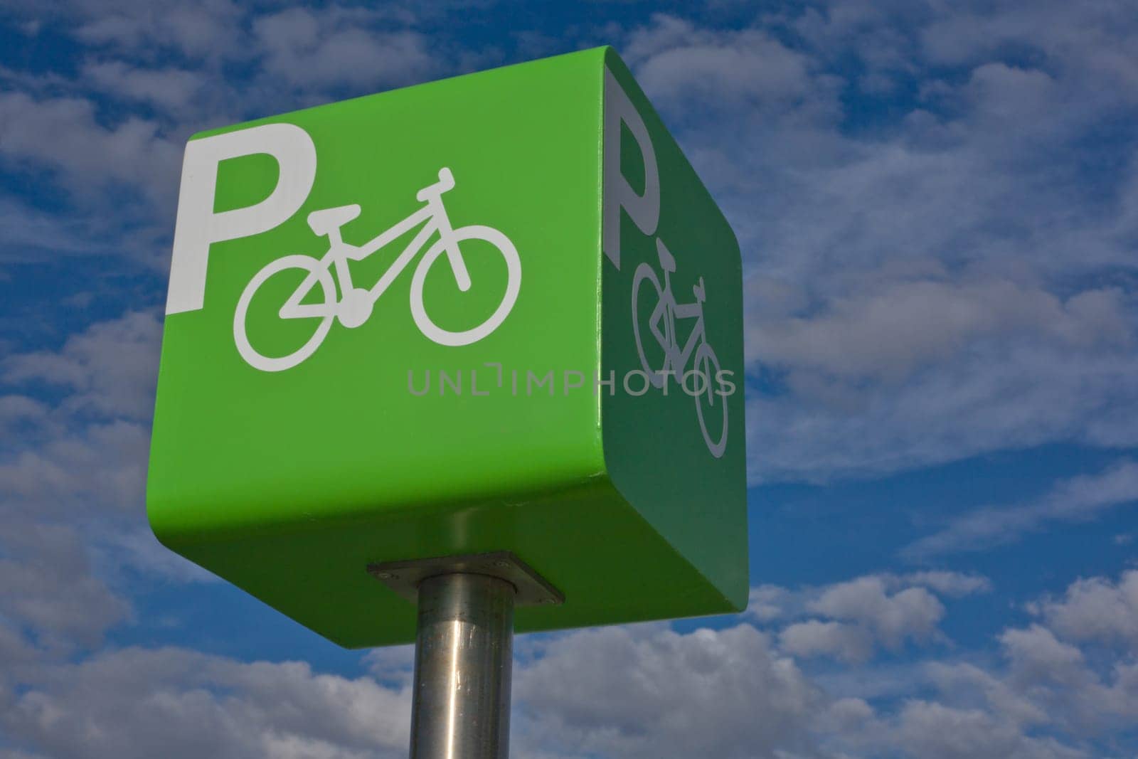 Green parking bicycle pole sign iver blue cloudy sky background