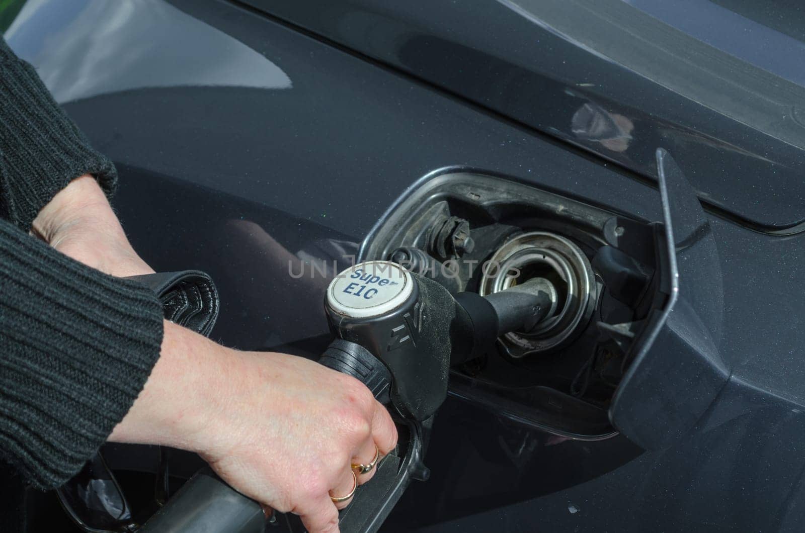 Women's hand refuelling a sports car with fuel E 10