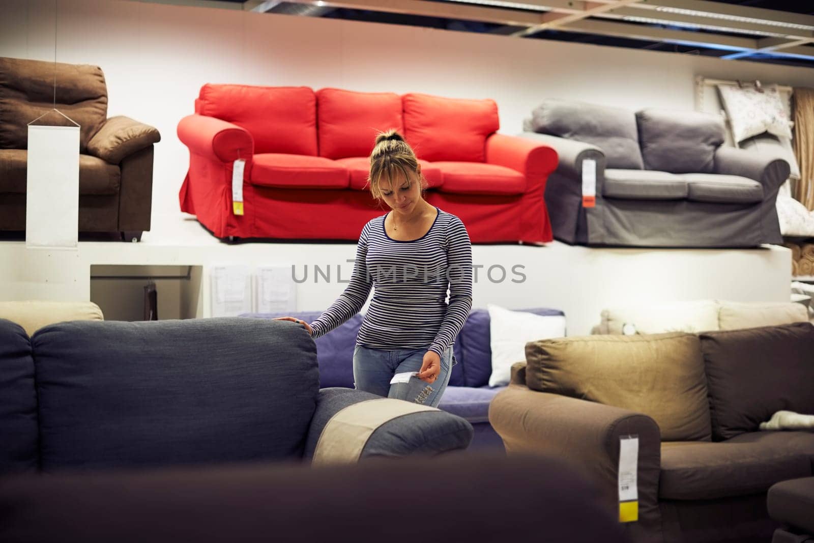 young hispanic woman shopping for furniture, sofa and home decor in store