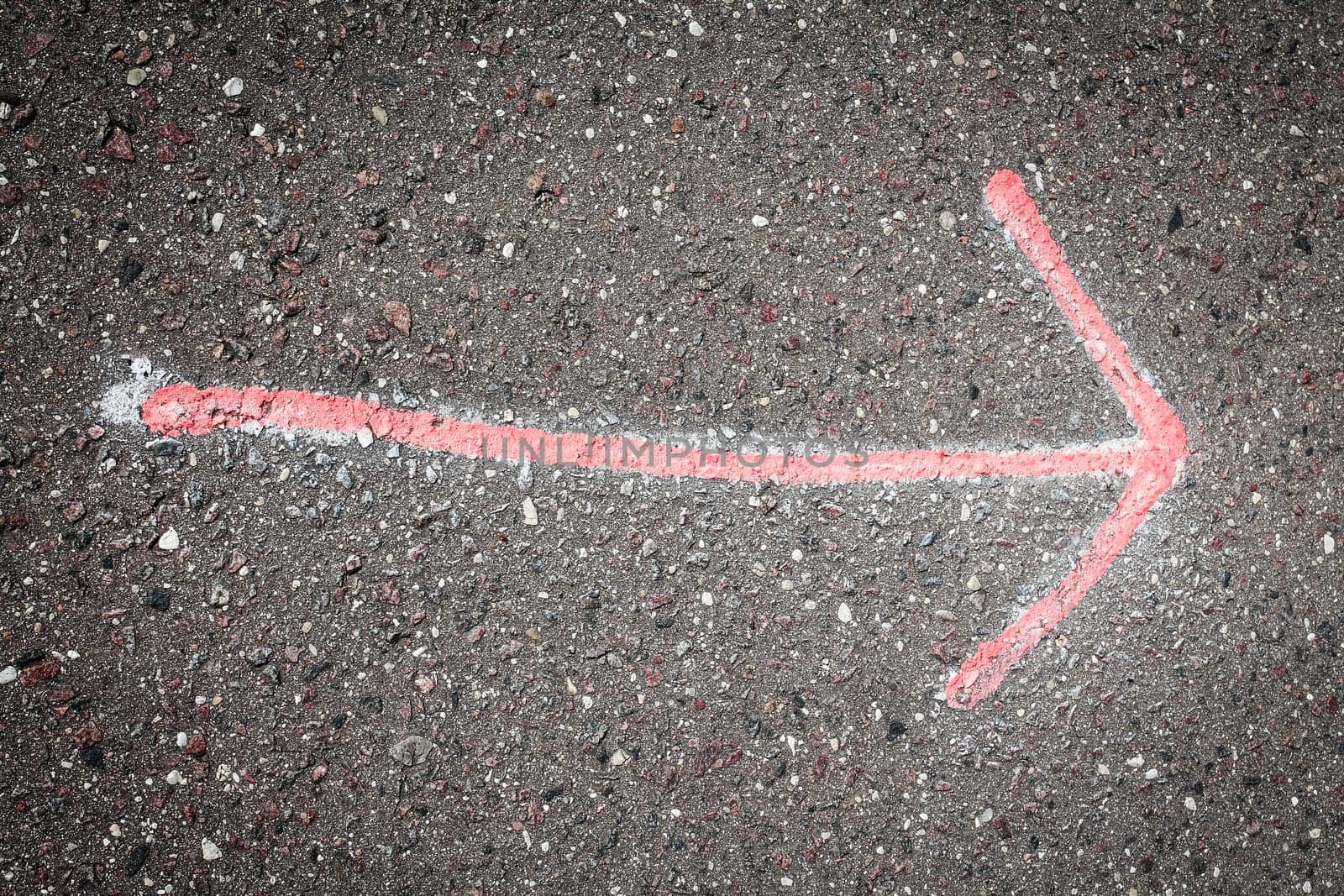 Hand drawn red  arrow on dark asphalt