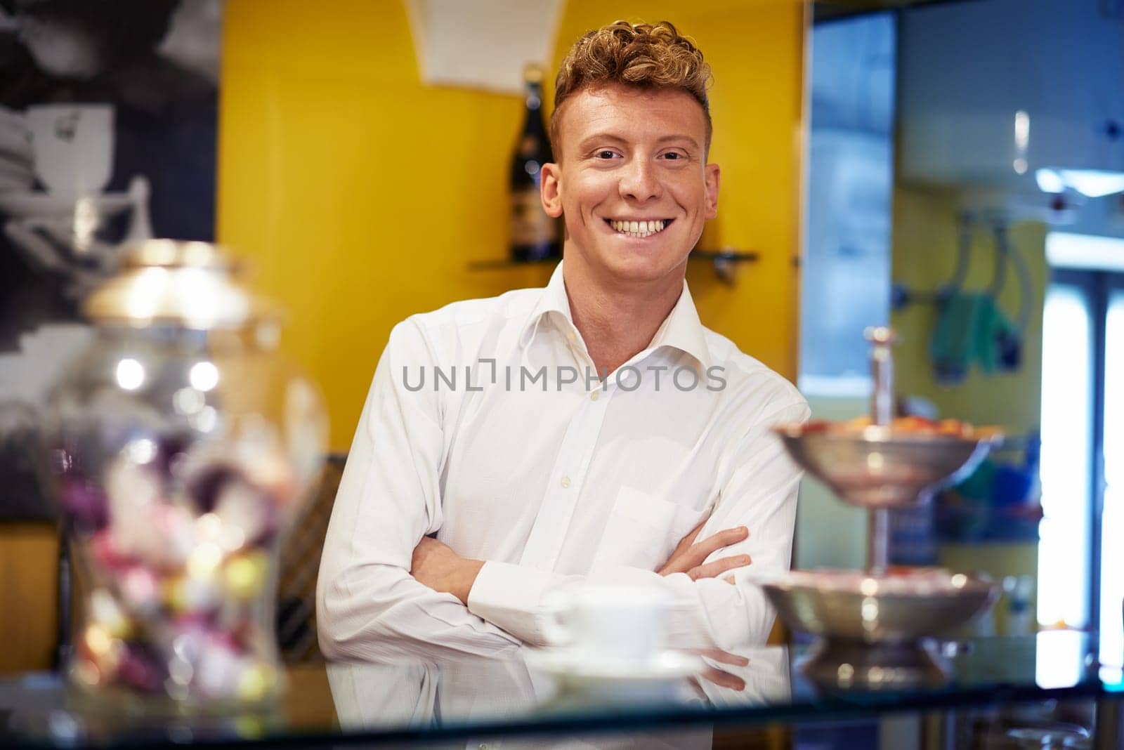 People in cafeteria, portrait of happy young man working as barman, smiling at camera behind counter