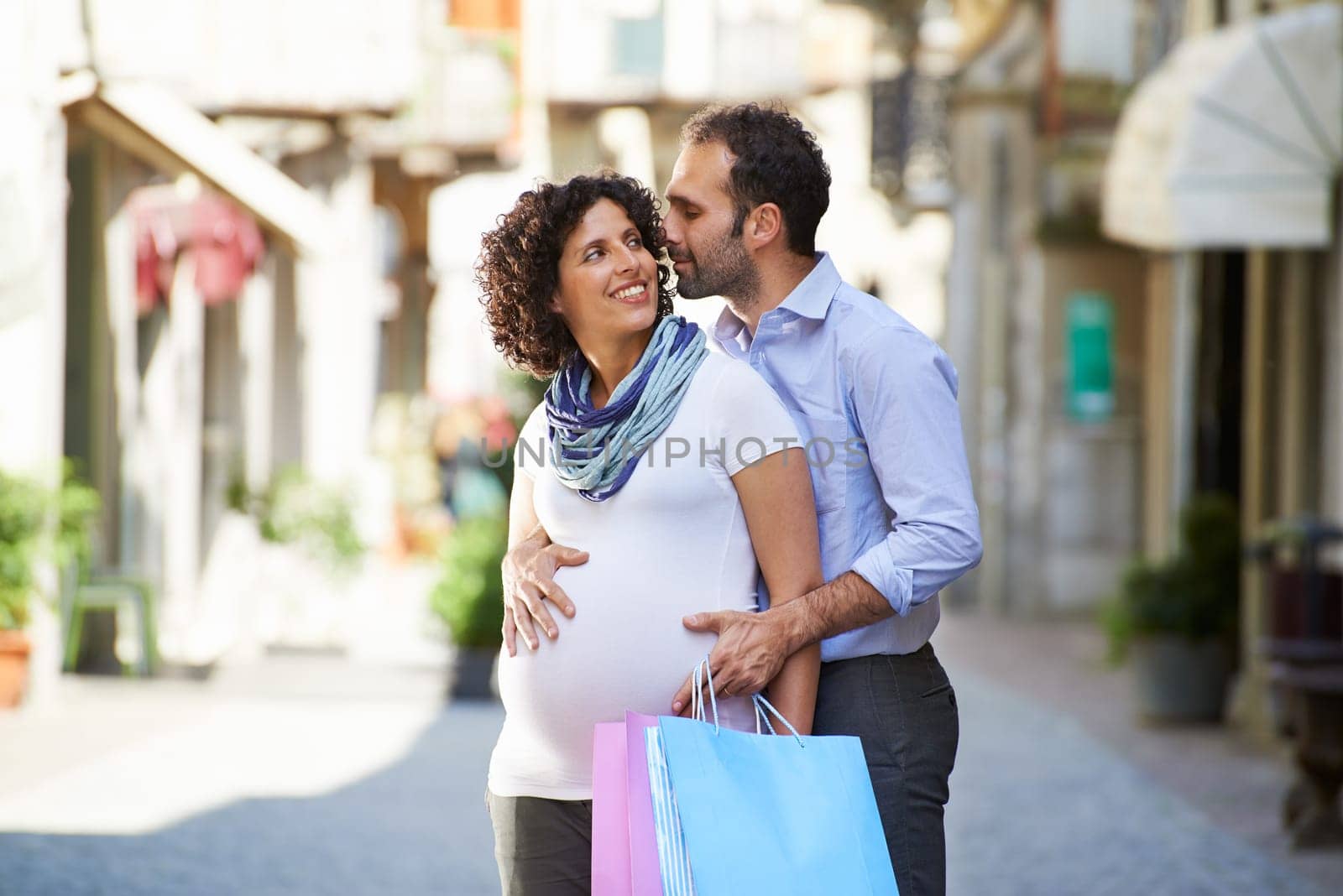 Portrait of happy people with husband and pregnant wife shopping and having fun in italian city street