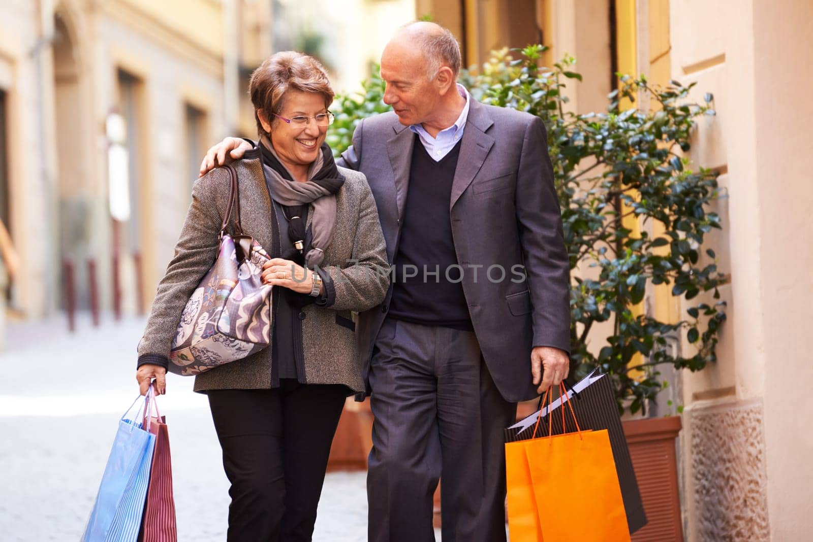 Happy people with senior man and woman shopping and walking with bags in italian city street