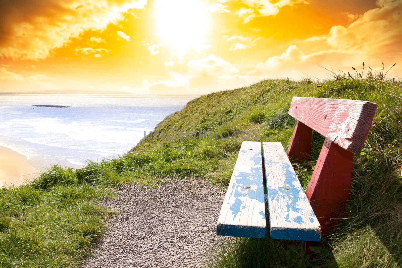 a scenic view of Ballybunion beach and Atlantic Ocean on a bright sunset evening from a bench