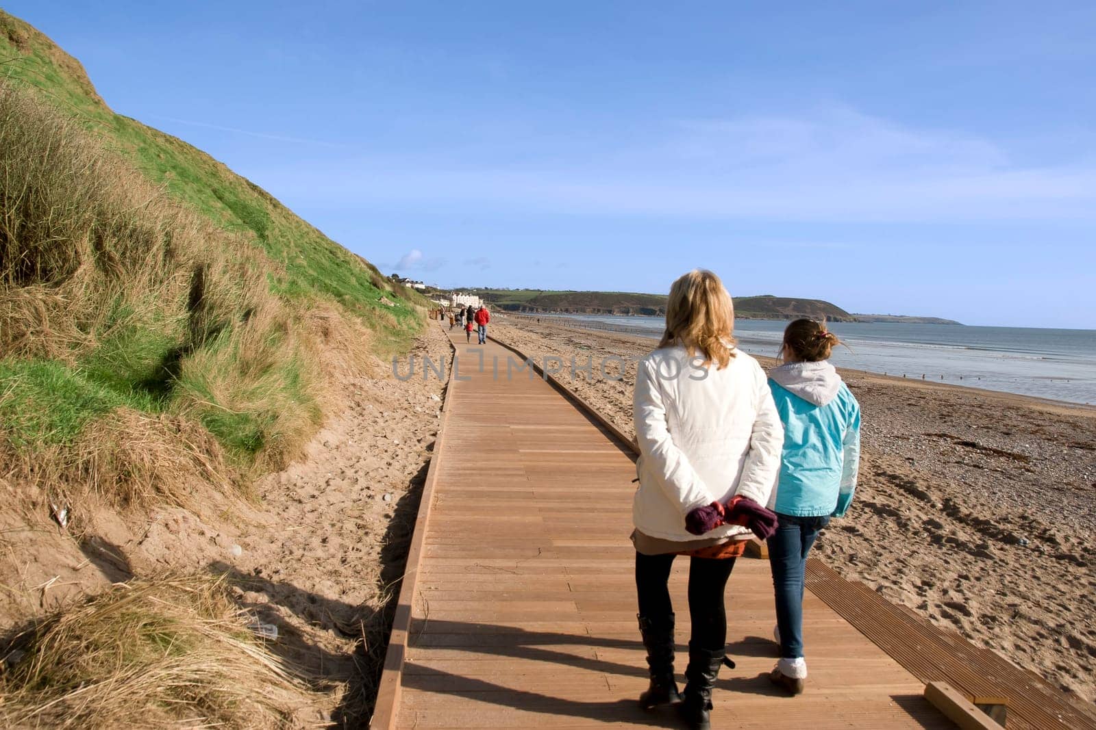mother and daughter strolling along the beach boardwalk in Youghal county Cork Ireland