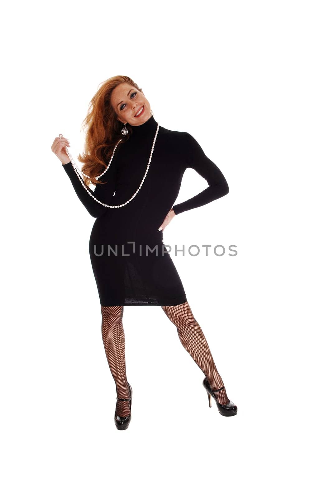 A middle aged woman standing from the front in a black dress isolated for.white background..