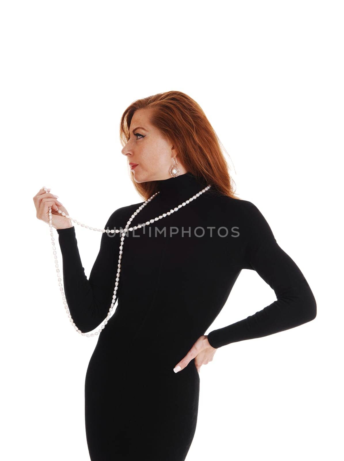 A middle aged woman standing in profile in a black dress isolated for.white background..