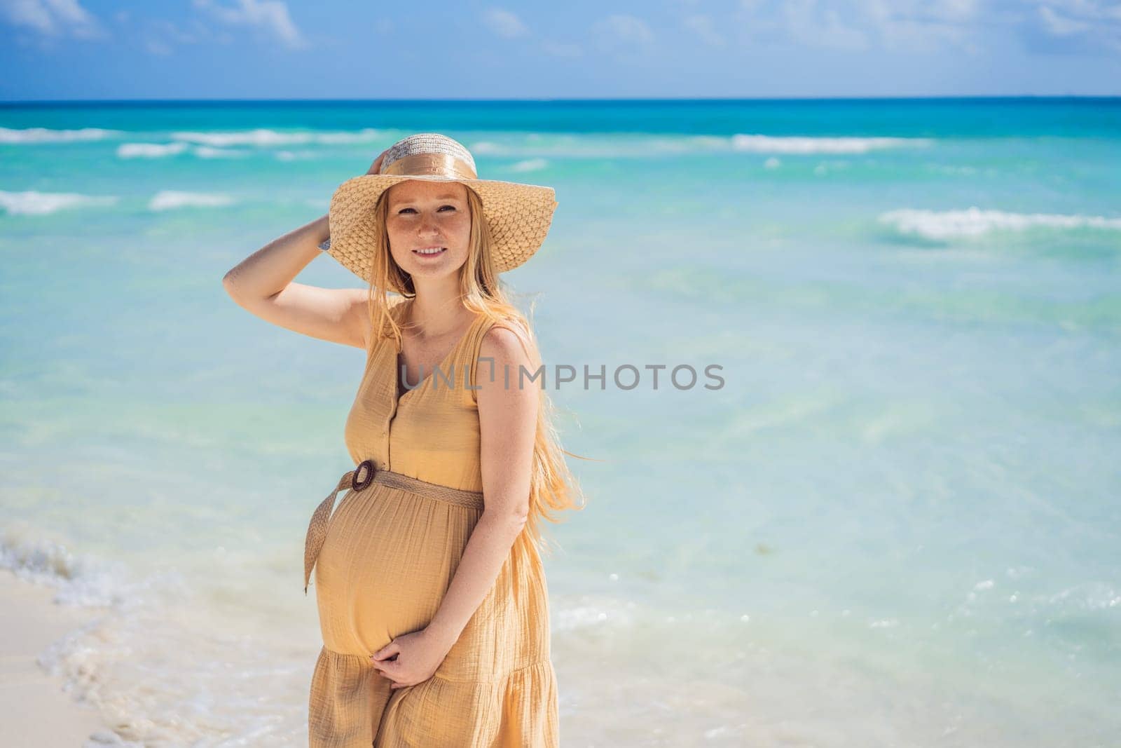 Radiant and expecting, a pregnant woman stands on a pristine snow-white tropical beach, celebrating the miracle of life against a backdrop of natural beauty.