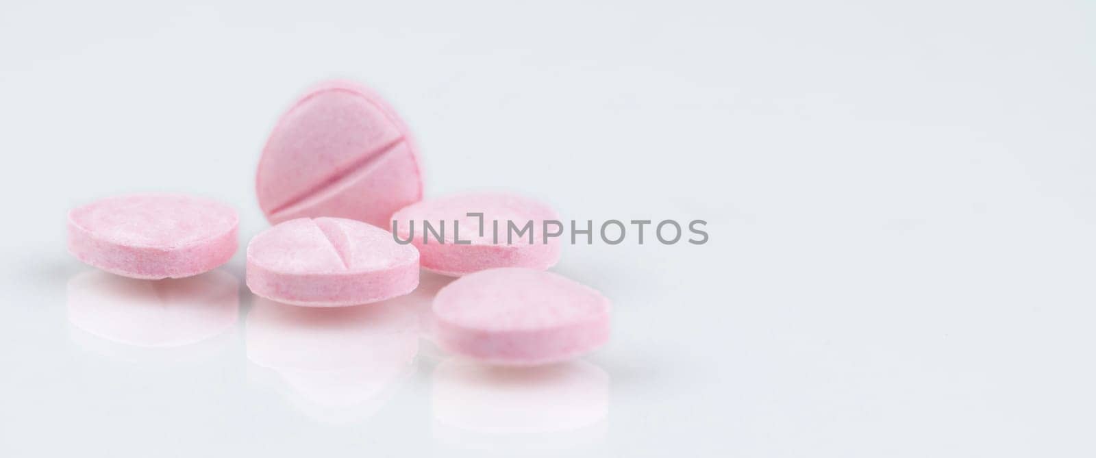 Pink tablets pills on white background. Health and medical care concept. Pharmacy banner. Prescription drug. Pharmaceutical industry. Medical center banner. Vitamins, minerals and supplements concept.