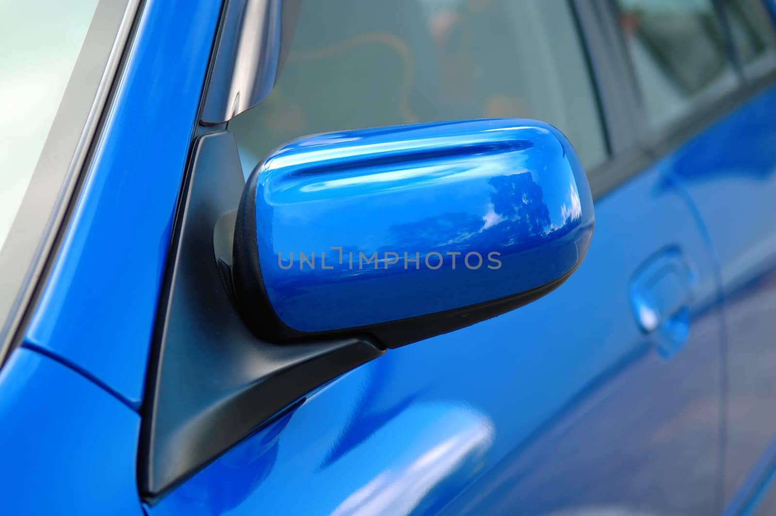 Close shot of right side mirror of shiny blue car