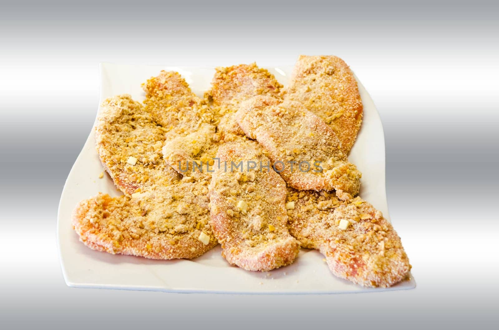Breaded schnitzel on a white plate with grey white background.