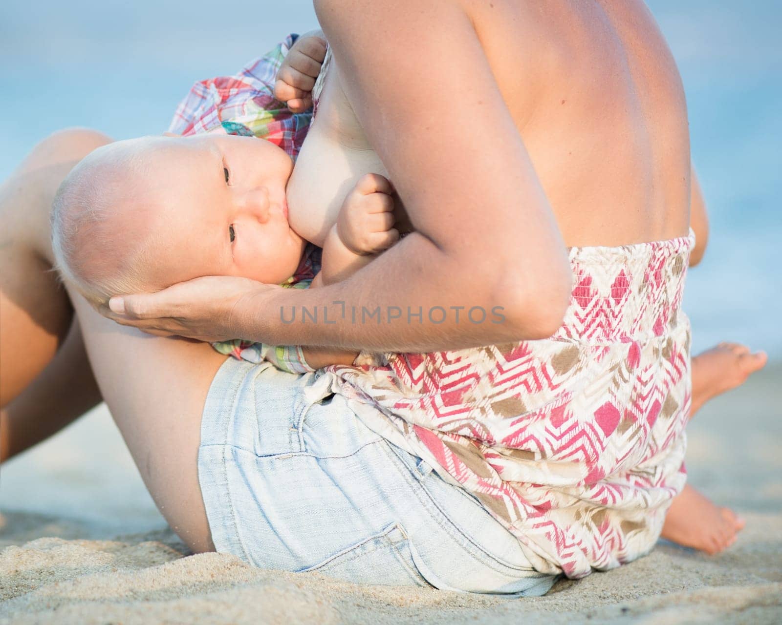 Mother breastfeeding baby on the beach