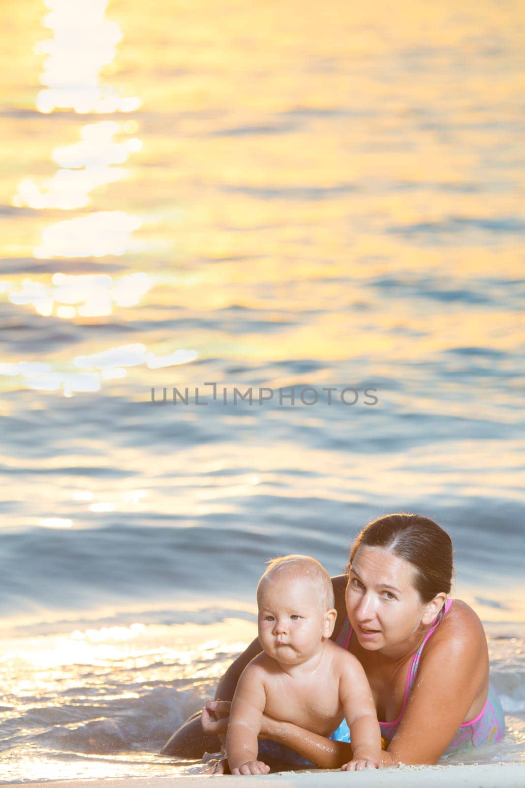 Baby and mother on the beach at sunset