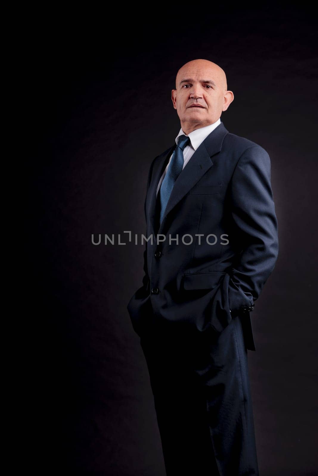 old bald self-confident businessman on a dark background