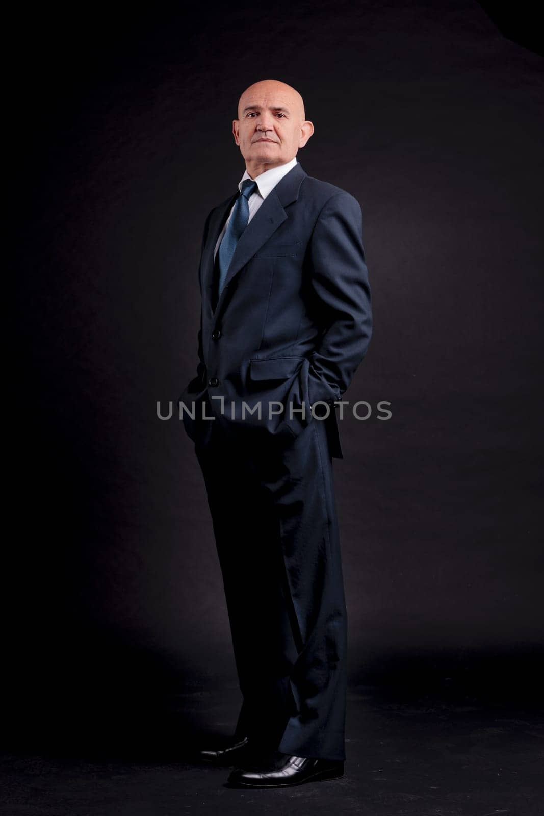 old bald self-confident businessman on a dark background