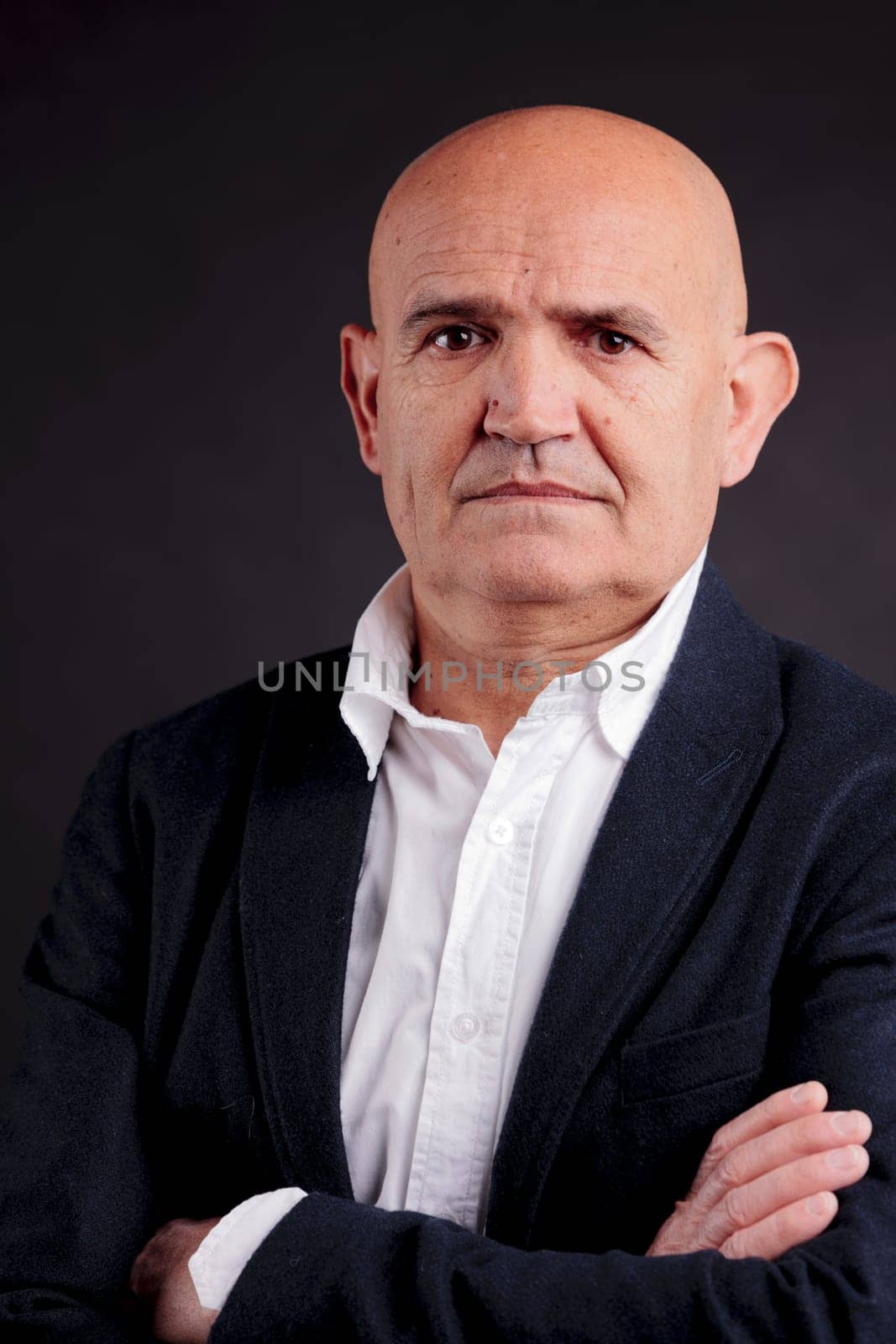 old bald self-confident businessman on a dark background